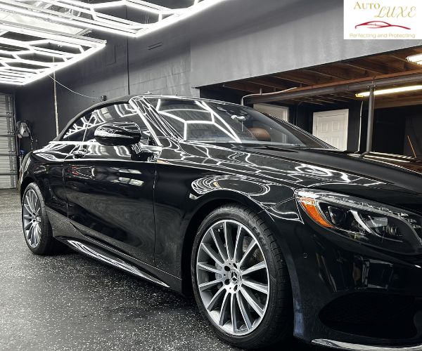 A side profile view of the luxury sedan, showcasing the clean, seamless application of dark window tint across both side windows under bright overhead workshop lighting.