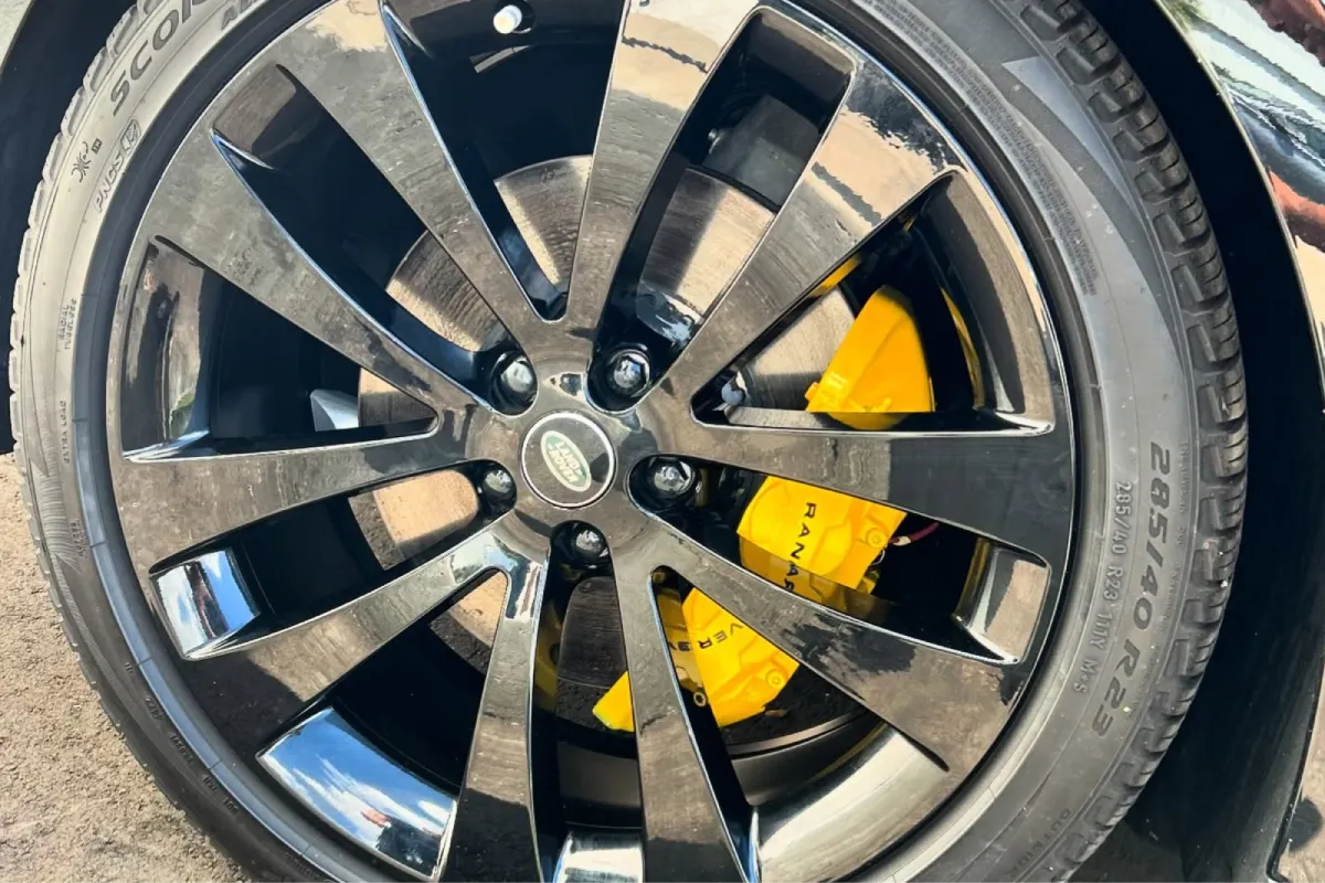 Bright yellow brake caliper visible through black Land Rover wheel after brake caliper painting.