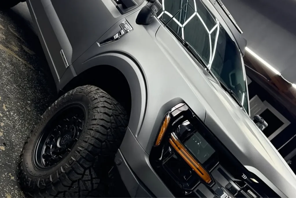 Matte grey Ford F-150 truck with off-road tires prepped for brake caliper painting.